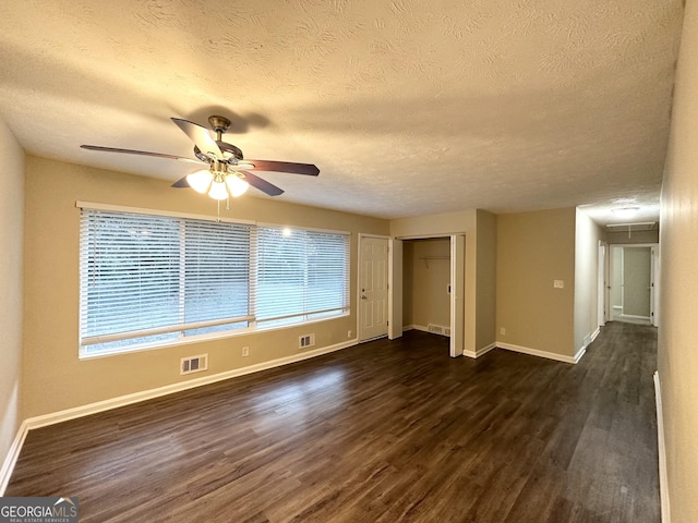 unfurnished room with ceiling fan, dark wood-type flooring, and a textured ceiling