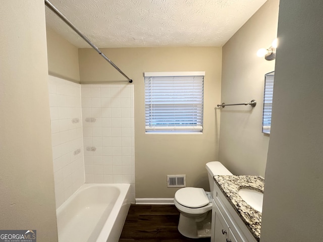 full bathroom featuring toilet, a textured ceiling, vanity, tiled shower / bath combo, and hardwood / wood-style floors