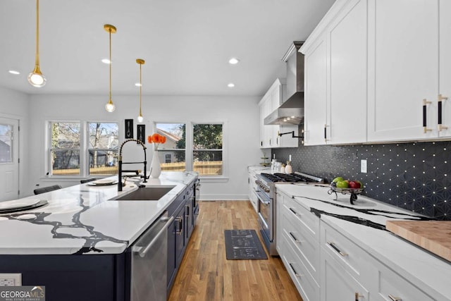 kitchen with sink, decorative light fixtures, a center island with sink, appliances with stainless steel finishes, and white cabinets