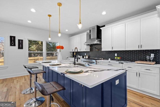 kitchen with white cabinetry, pendant lighting, an island with sink, and wall chimney exhaust hood