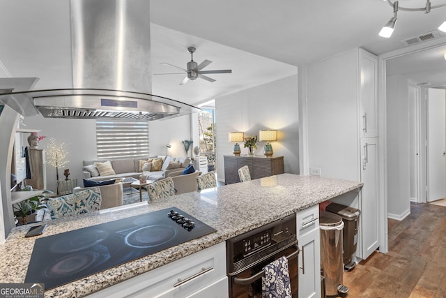 kitchen featuring white cabinetry, island range hood, light stone counters, and black appliances