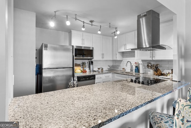 kitchen featuring backsplash, stainless steel appliances, island exhaust hood, white cabinets, and a kitchen bar