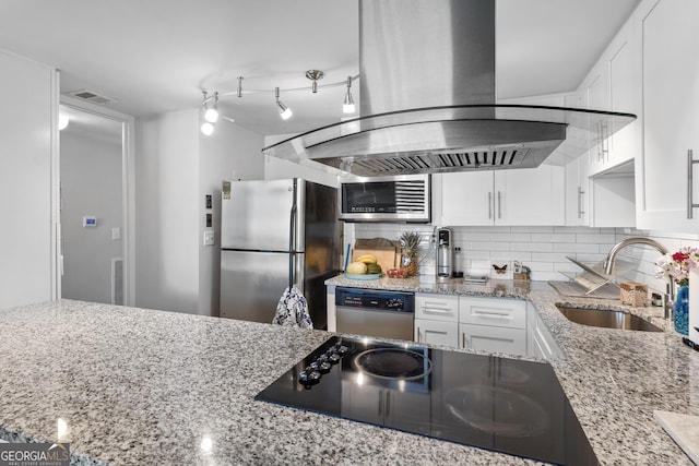 kitchen with sink, white cabinetry, island exhaust hood, stainless steel appliances, and light stone countertops