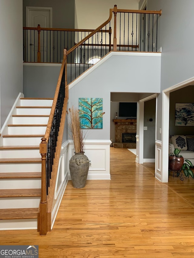 stairs featuring hardwood / wood-style flooring, a towering ceiling, and a fireplace