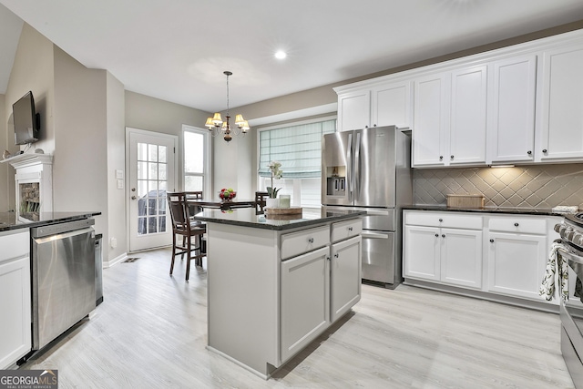 128 Greenview Dr, Newnan, GA 30265 - kitchen featuring tasteful backsplash, light wood-type flooring, an inviting chandelier, appliances with stainless steel finishes, and a kitchen island