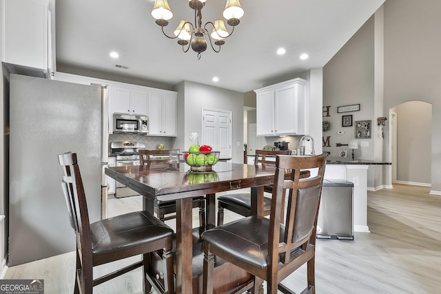 128 Greenview Dr, Newnan, GA 30265 - dining room featuring a chandelier, arched walkways, light wood finished floors, baseboards, and visible vents