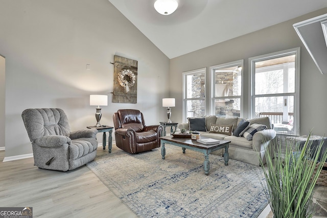 living room with a wealth of natural light, high vaulted ceiling, and wood-type flooring