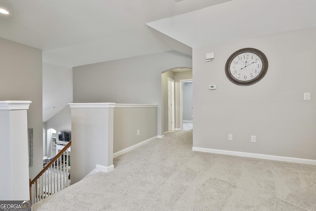 corridor featuring vaulted ceiling and light carpet