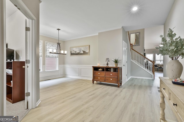 interior space with ornamental molding, an inviting chandelier, and light hardwood / wood-style floors