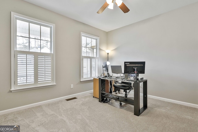 home office with plenty of natural light, light carpet, and ceiling fan