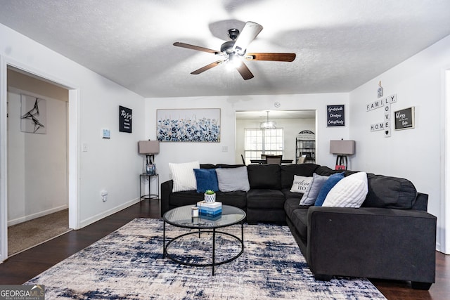 living room featuring ceiling fan, dark wood-type flooring, and a textured ceiling