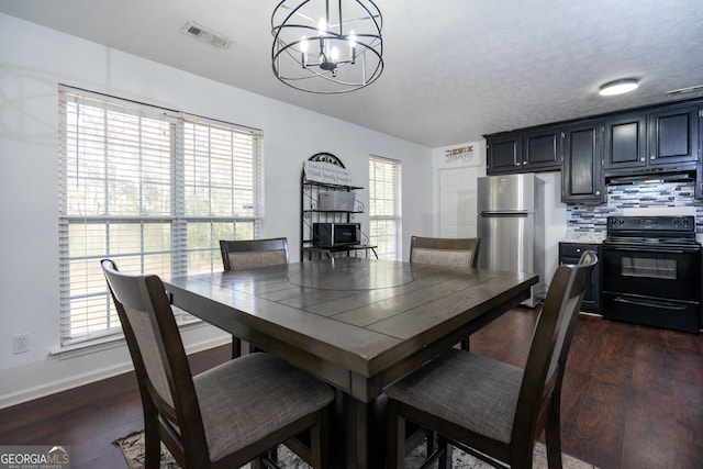 dining space featuring dark wood-type flooring, a notable chandelier, and a textured ceiling