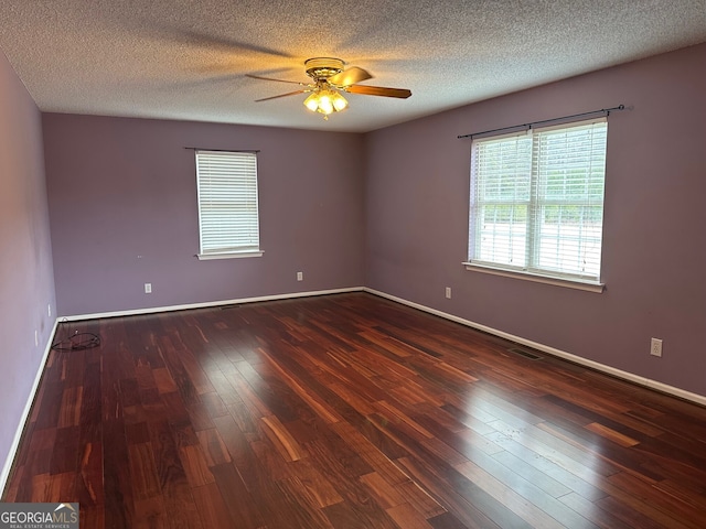 empty room with ceiling fan, dark hardwood / wood-style floors, and a textured ceiling