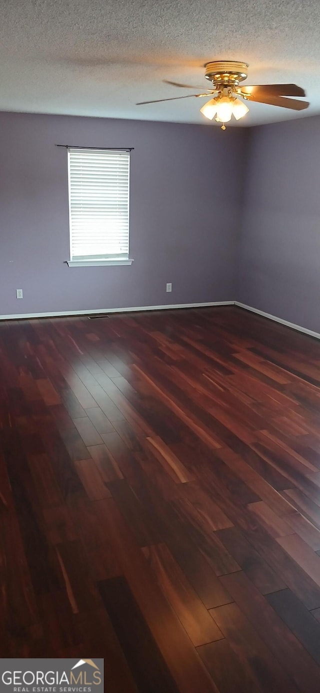 empty room with ceiling fan, dark hardwood / wood-style floors, and a textured ceiling