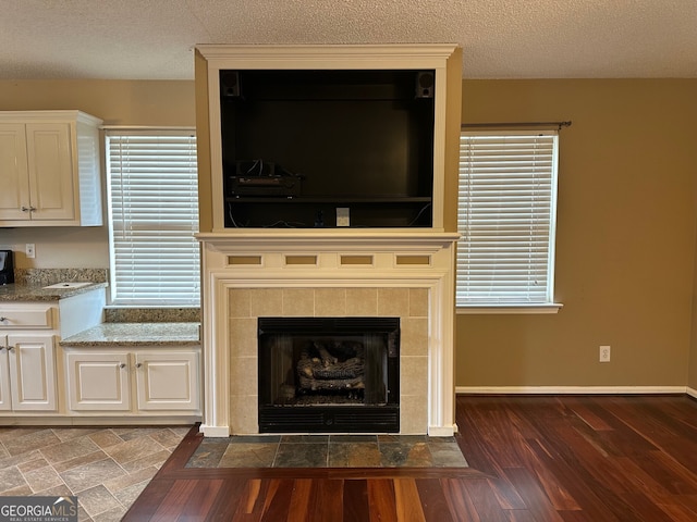 details featuring a tiled fireplace, hardwood / wood-style floors, and a textured ceiling