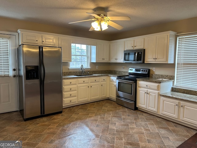 kitchen with dark stone countertops, sink, stainless steel appliances, and white cabinets