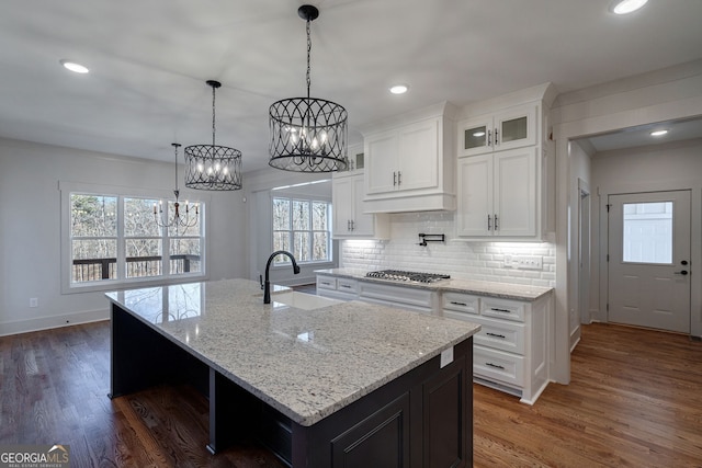 kitchen with white cabinetry, dark hardwood / wood-style floors, sink, and a center island with sink