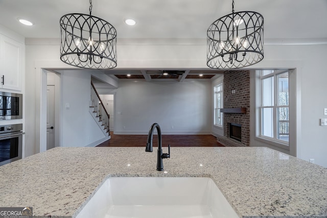 kitchen with pendant lighting, stainless steel appliances, light stone countertops, and an inviting chandelier