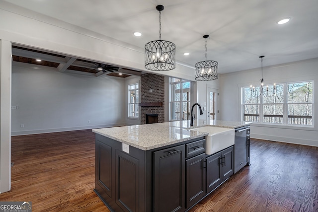 kitchen featuring pendant lighting, dishwasher, an island with sink, sink, and dark hardwood / wood-style flooring