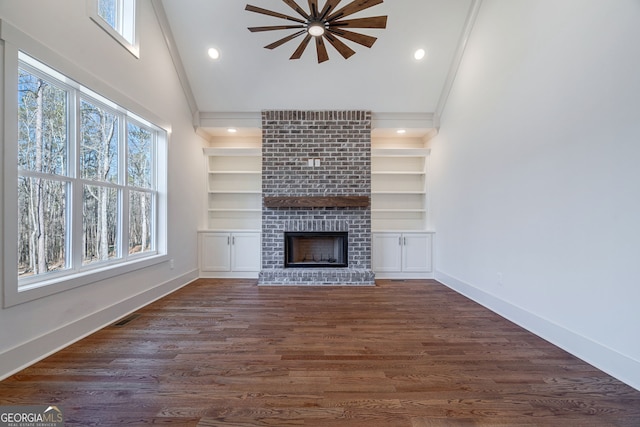 unfurnished living room featuring a brick fireplace, built in shelves, and dark wood-type flooring