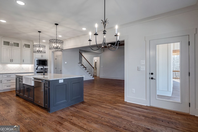 kitchen with appliances with stainless steel finishes, pendant lighting, tasteful backsplash, an island with sink, and white cabinets