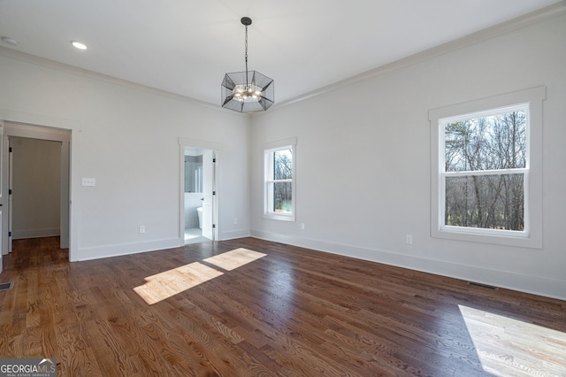 spare room featuring crown molding, dark hardwood / wood-style flooring, and an inviting chandelier