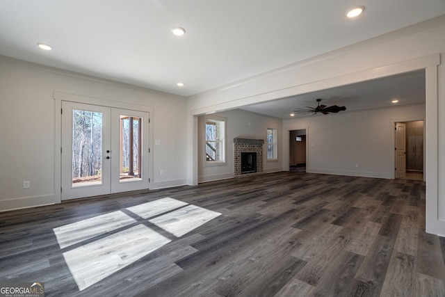 unfurnished living room with french doors, a fireplace, dark hardwood / wood-style floors, and ceiling fan