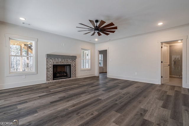 unfurnished living room featuring a brick fireplace, dark hardwood / wood-style floors, and ceiling fan