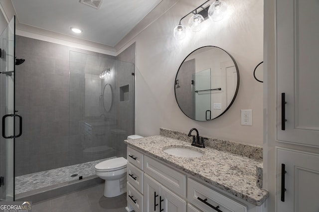 bathroom with vanity, a shower with shower door, tile patterned floors, and toilet