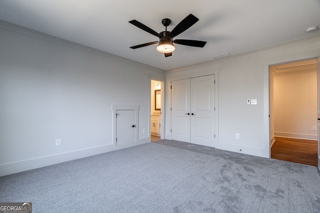 unfurnished bedroom with ceiling fan, ensuite bath, carpet floors, and a closet