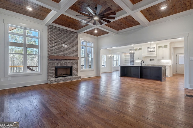 unfurnished living room featuring coffered ceiling, beam ceiling, and dark hardwood / wood-style flooring