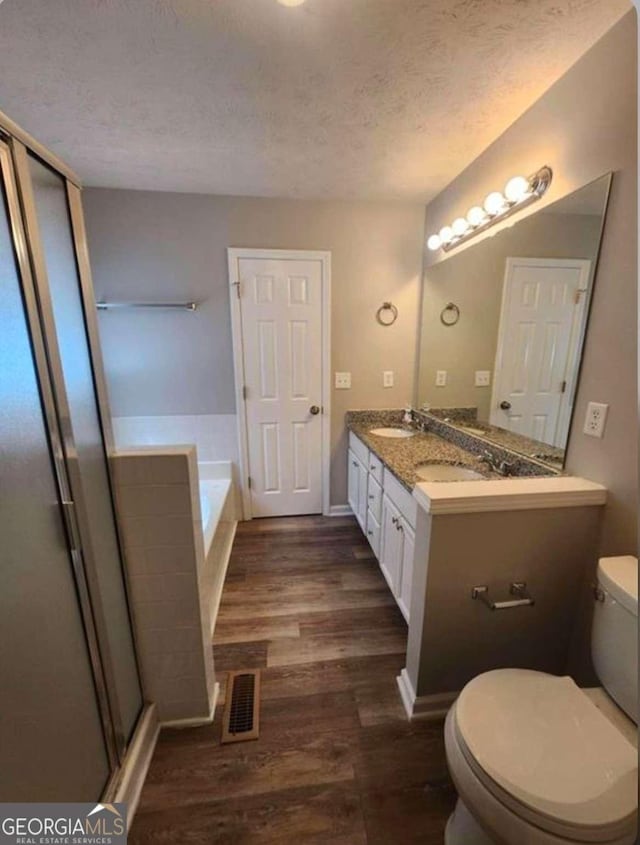 full bathroom with toilet, wood-type flooring, separate shower and tub, a textured ceiling, and vanity