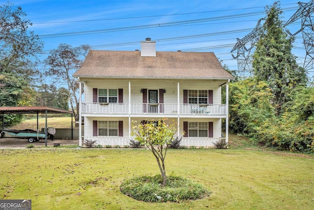 rear view of house with a carport, covered porch, and a lawn