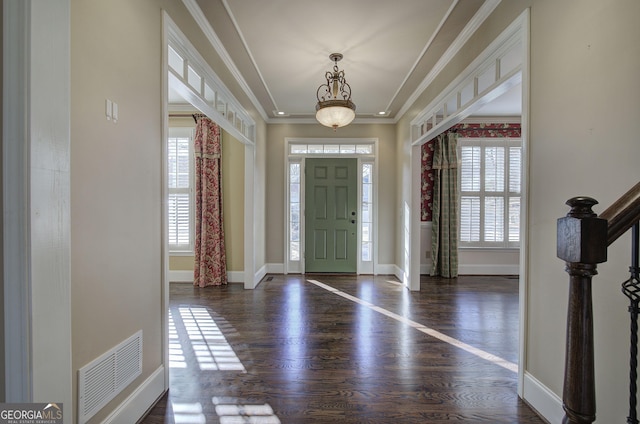 foyer entrance with ornamental molding, a healthy amount of sunlight, and dark wood-type flooring