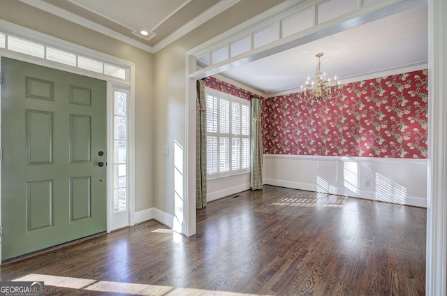 entryway with dark wood-type flooring, ornamental molding, and a notable chandelier