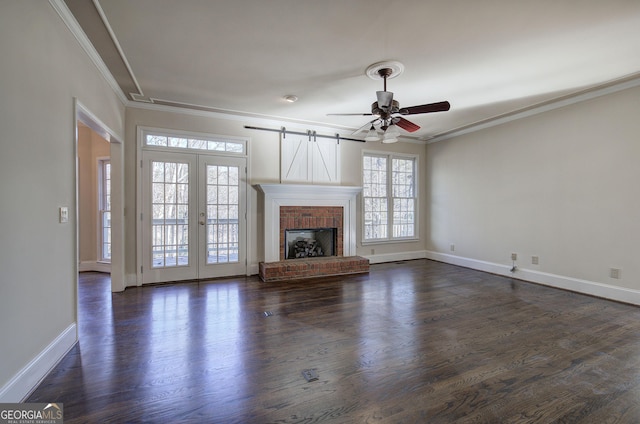 unfurnished living room with french doors, crown molding, a brick fireplace, dark hardwood / wood-style floors, and ceiling fan