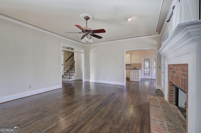 unfurnished living room with dark hardwood / wood-style flooring, ornamental molding, ceiling fan, and a fireplace