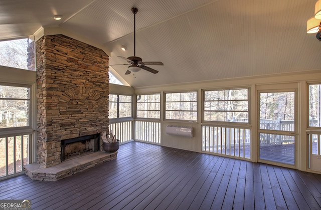 unfurnished sunroom with ceiling fan, lofted ceiling, and a stone fireplace