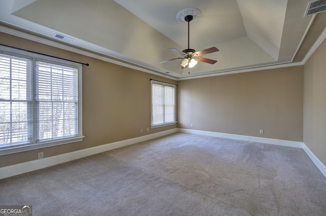 unfurnished room featuring a raised ceiling, ornamental molding, carpet, and ceiling fan