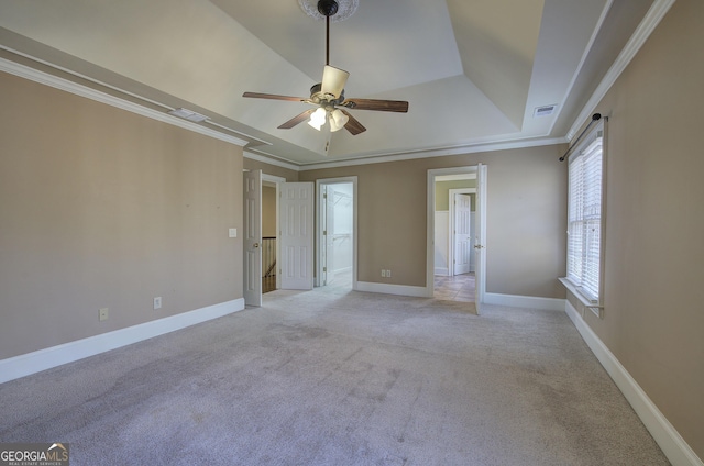 carpeted spare room featuring ceiling fan, ornamental molding, and a tray ceiling