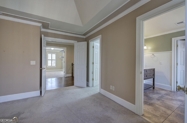 carpeted spare room with crown molding and vaulted ceiling