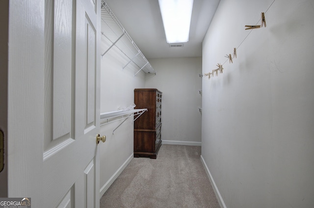 walk in closet with light carpet