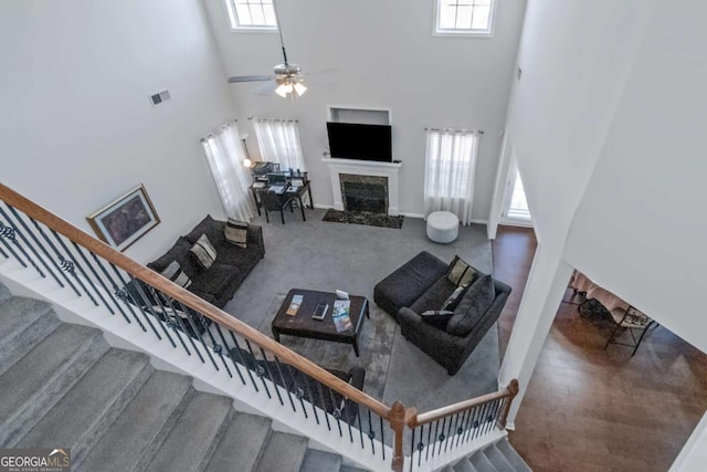 living room with a towering ceiling, plenty of natural light, and a high end fireplace