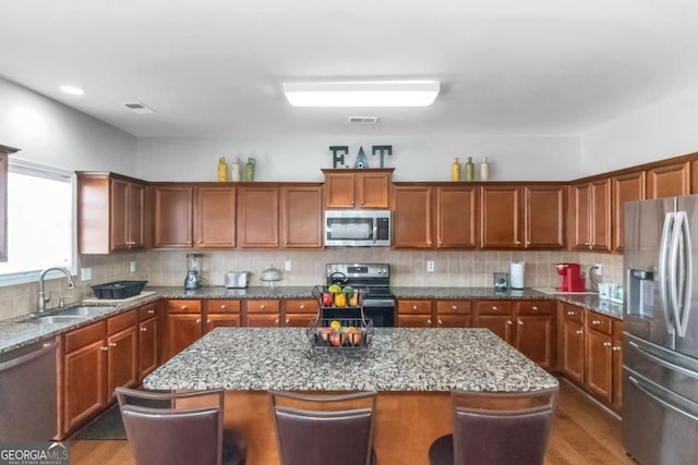 kitchen with a kitchen island, appliances with stainless steel finishes, sink, and a breakfast bar area