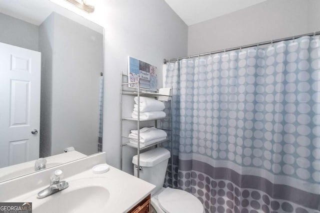 bathroom featuring vanity, curtained shower, and toilet