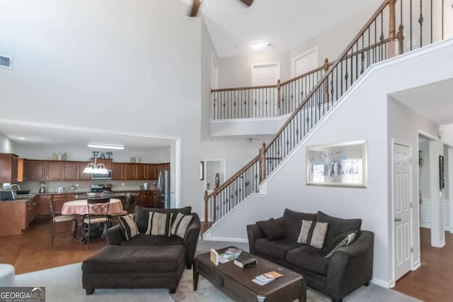 living room featuring a towering ceiling, sink, and light hardwood / wood-style floors