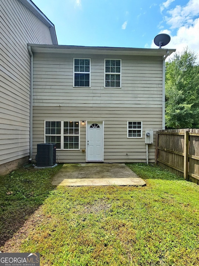 rear view of property featuring a patio, central AC, and a lawn