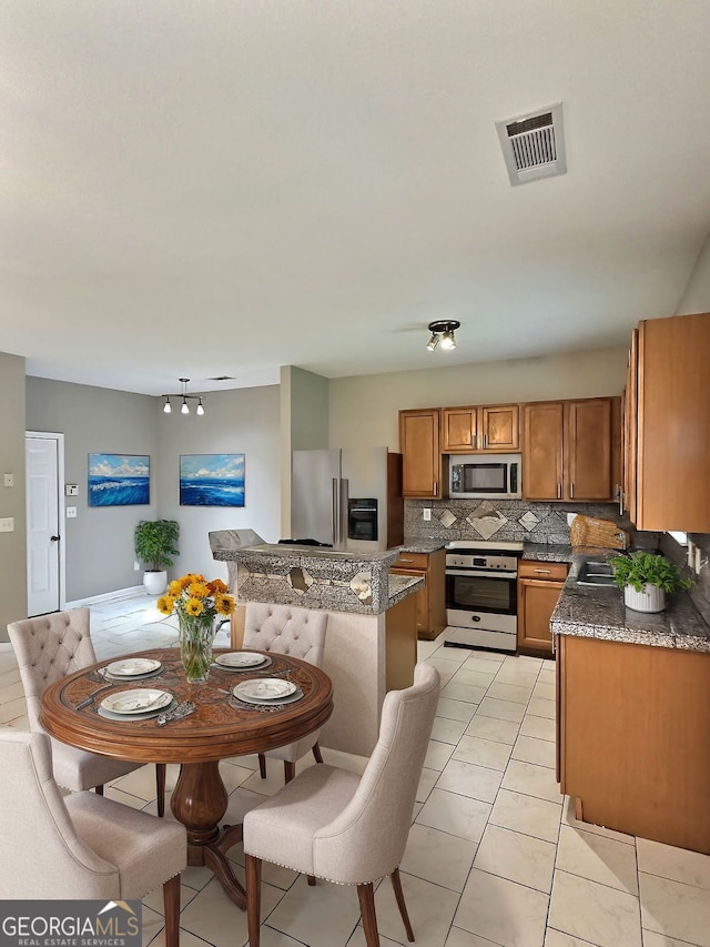 kitchen with tasteful backsplash, sink, dark stone countertops, light tile patterned floors, and stainless steel appliances