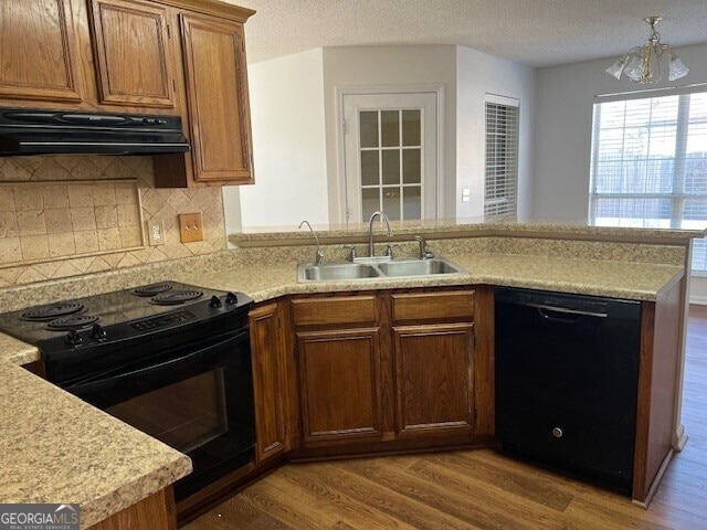 kitchen featuring range hood, sink, kitchen peninsula, and black appliances