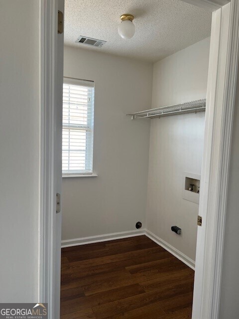 washroom featuring dark hardwood / wood-style floors, hookup for a washing machine, and a textured ceiling